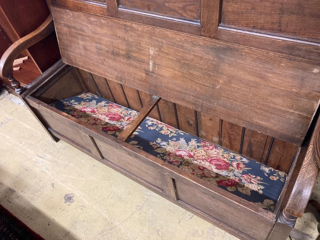 A mid 18th century panelled oak hinged box seat settle, length 148cm, depth 56cm, height 122cm